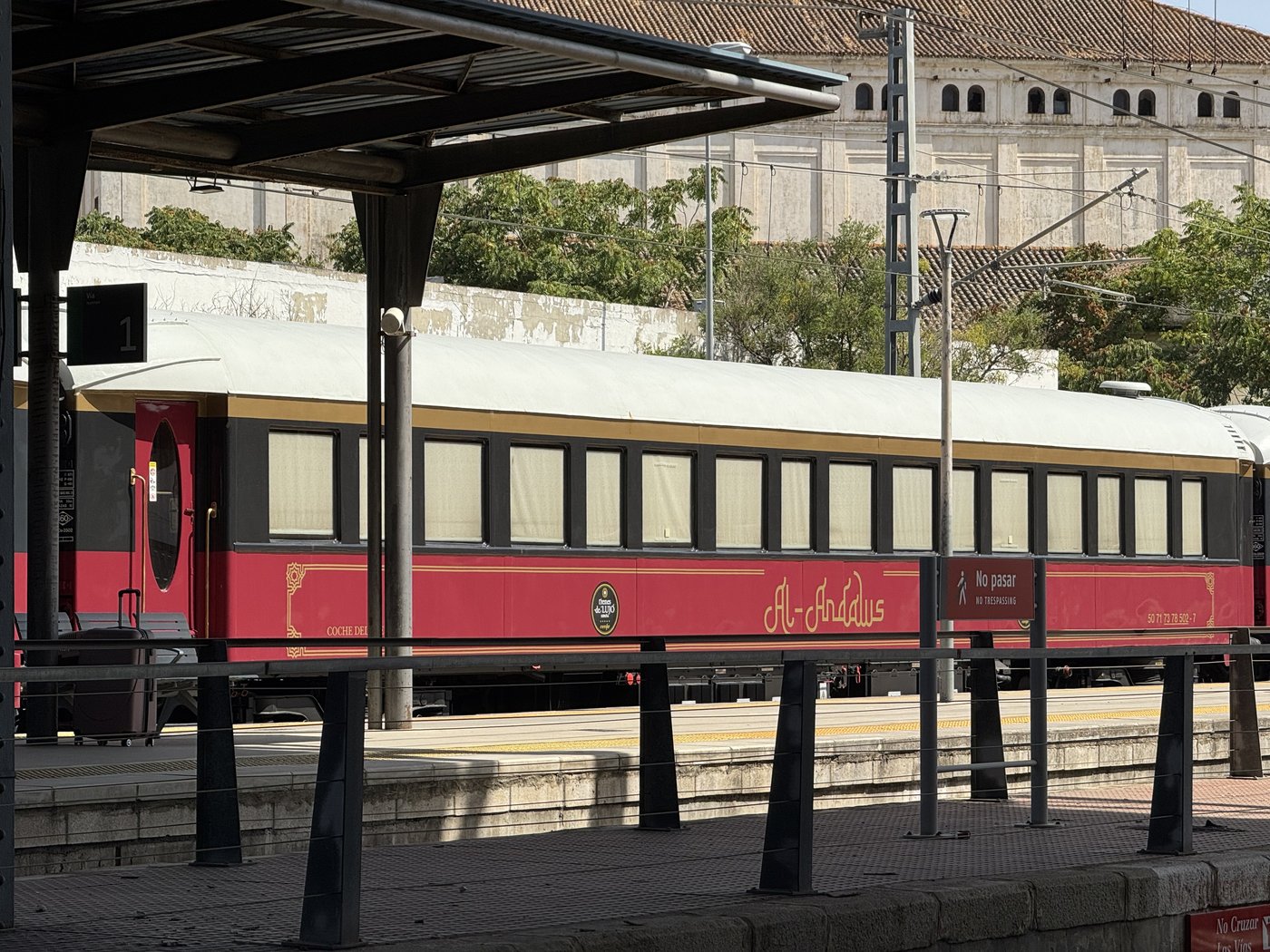 Ein dunkelroter historischer Eisenbahnwaggon mit cremefarbenem Fensterband steht unter einer Bahnsteigüberdachung.