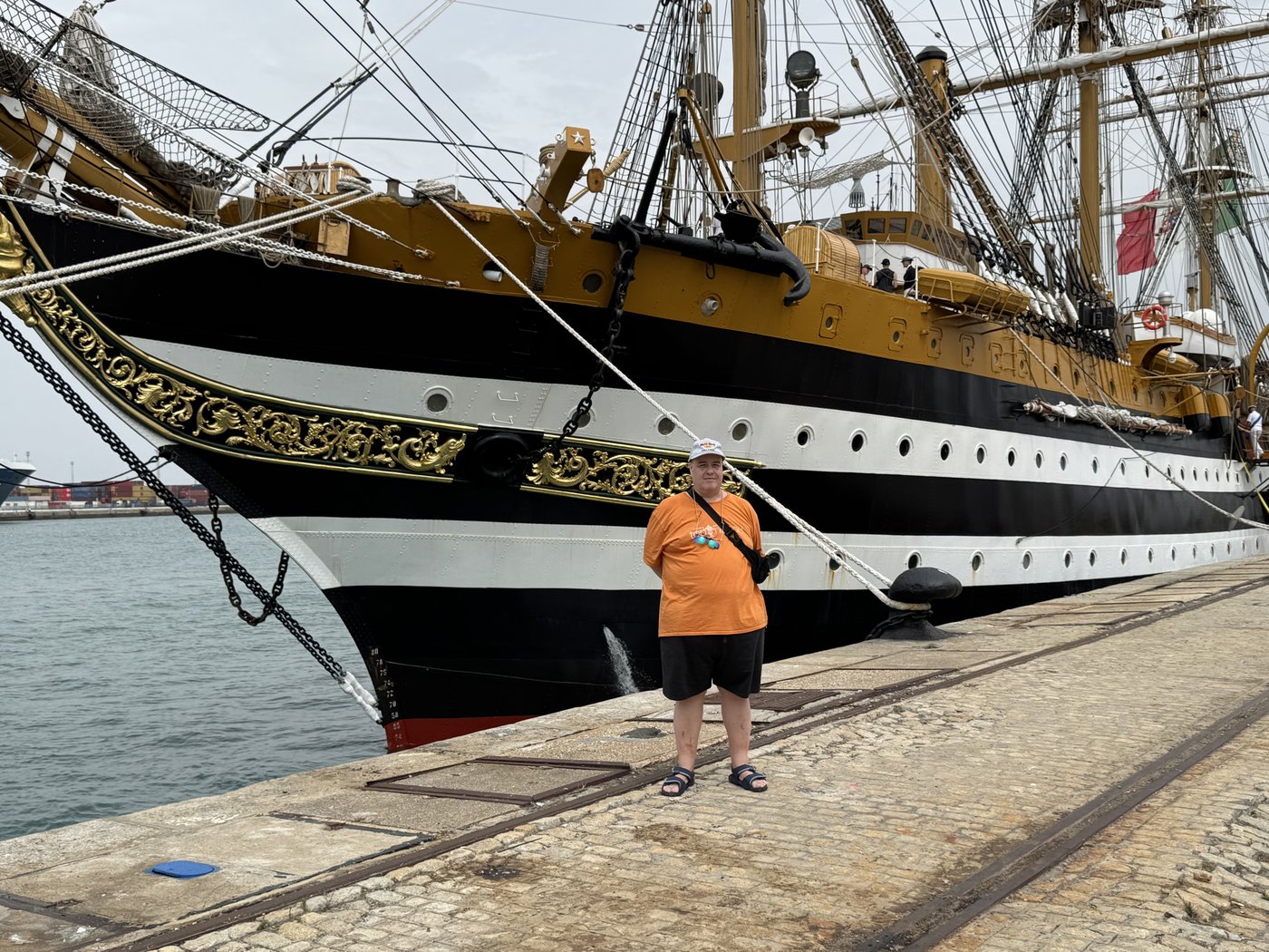 Der dunkle Rumpf der Amerigo Vespucci mit weißem Zierstreifen liegt am Kai, davor der Bugspriet und das Tauwerk.