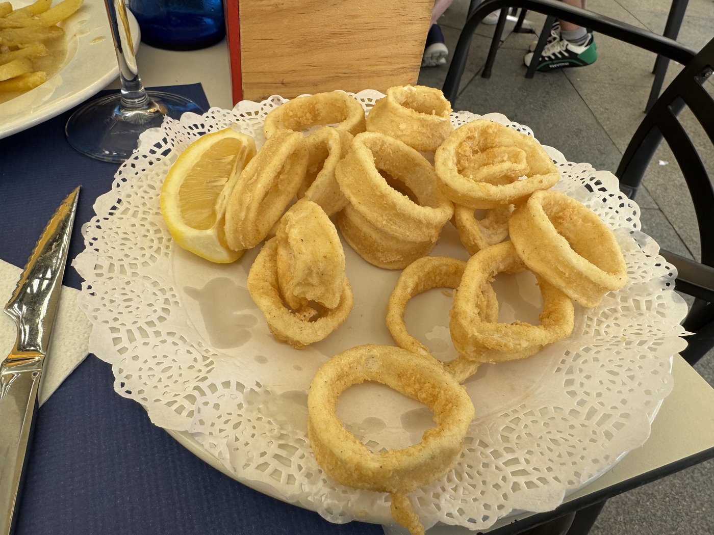 Ein Teller mit goldbraun frittierten Tintenfischringen auf einer weißen Papierserviette.
